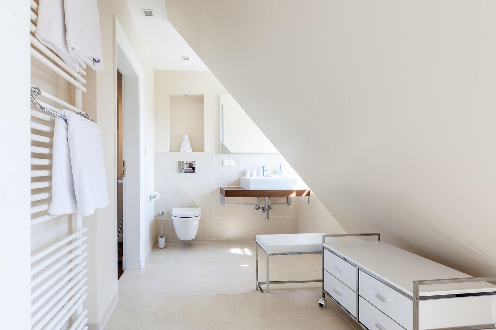 Bathroom with shower, sink, and toilet under sloped ceiling