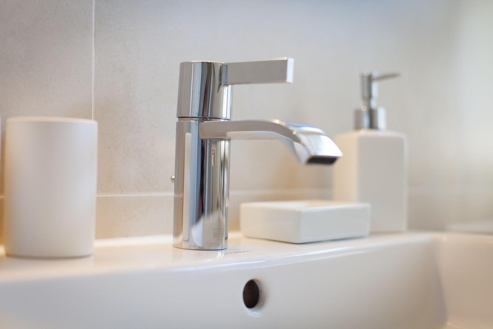 Sink with modern faucet and white accessories.