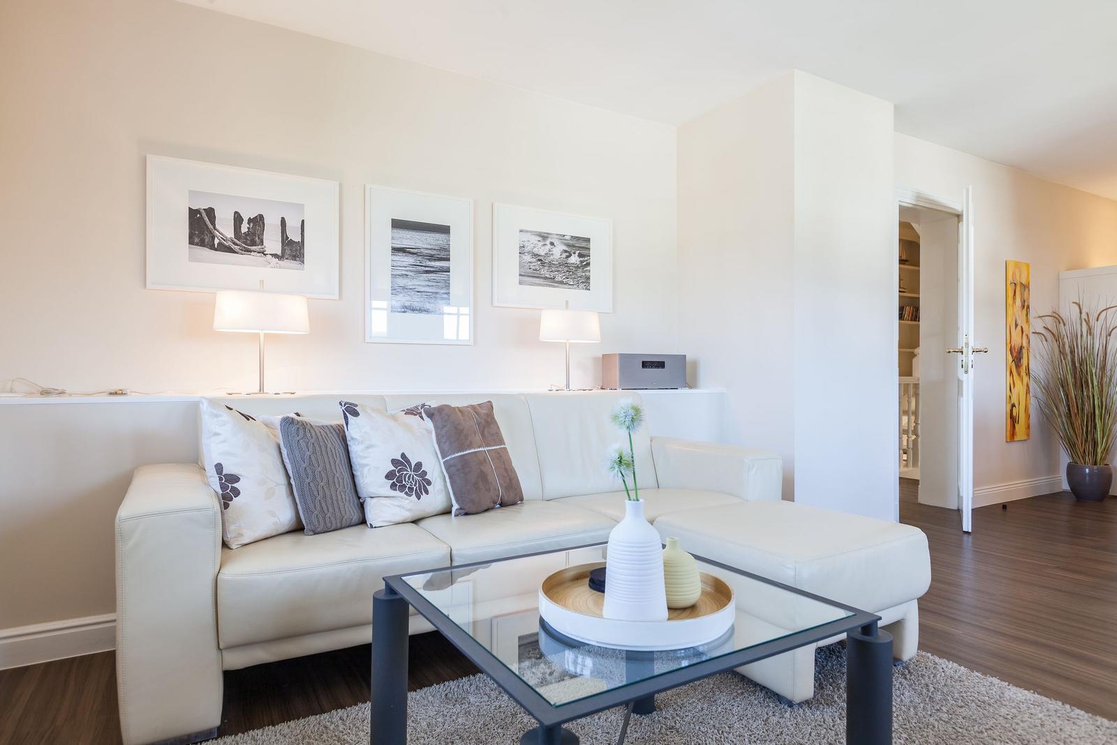 Living room with white sofa, glass table, and wall art.