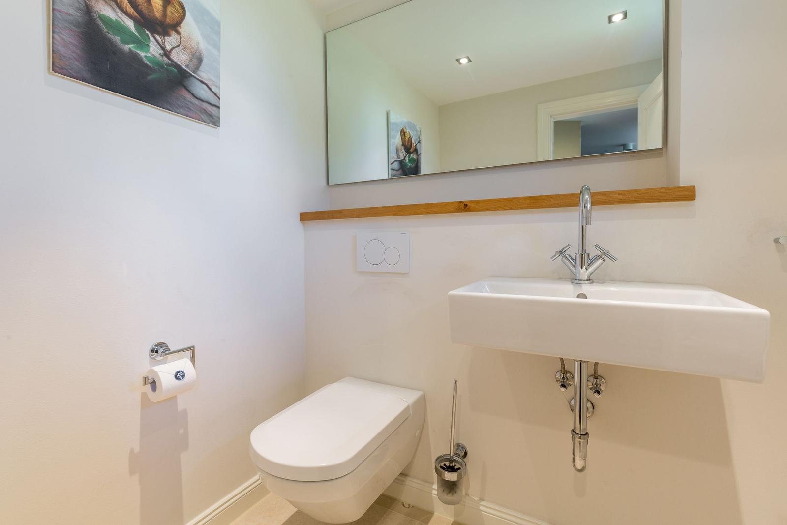 Badezimmer mit Waschbecken, Spiegel und Toilette.