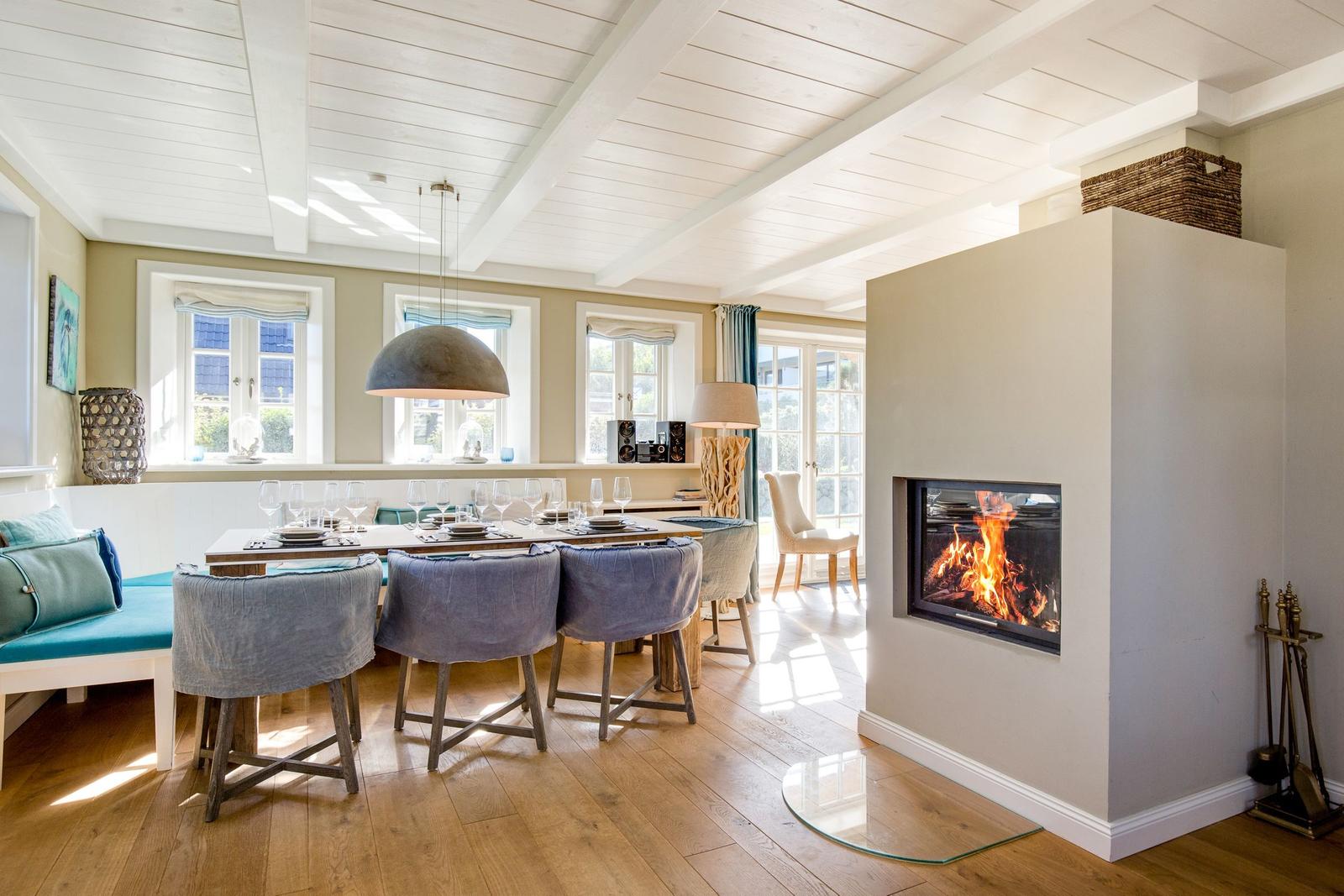 Esszimmer mit Feuerkamin und Holzboden. Tisch mit Stühlen und Fenstern.