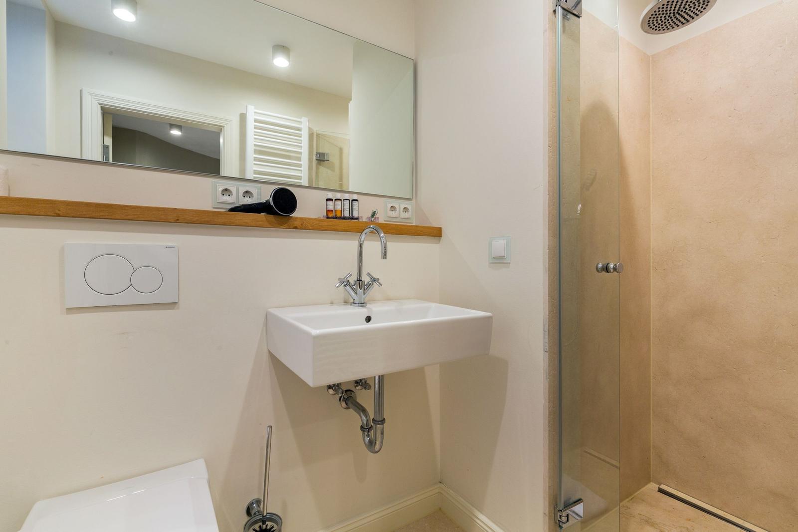 Badezimmer mit Waschbecken, Spiegel und Dusche.