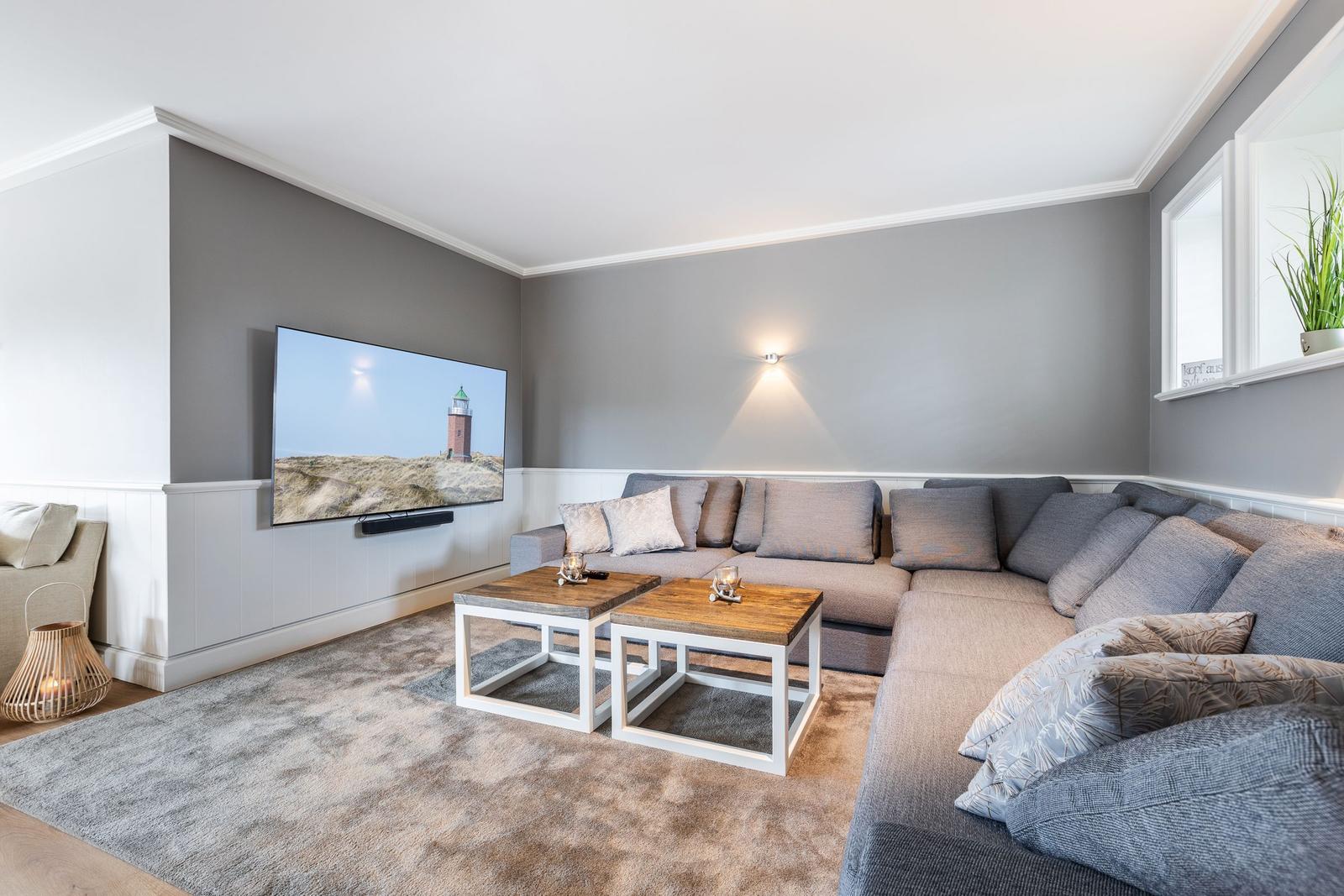 Living room with sectional sofa, TV, and two coffee tables on carpet.