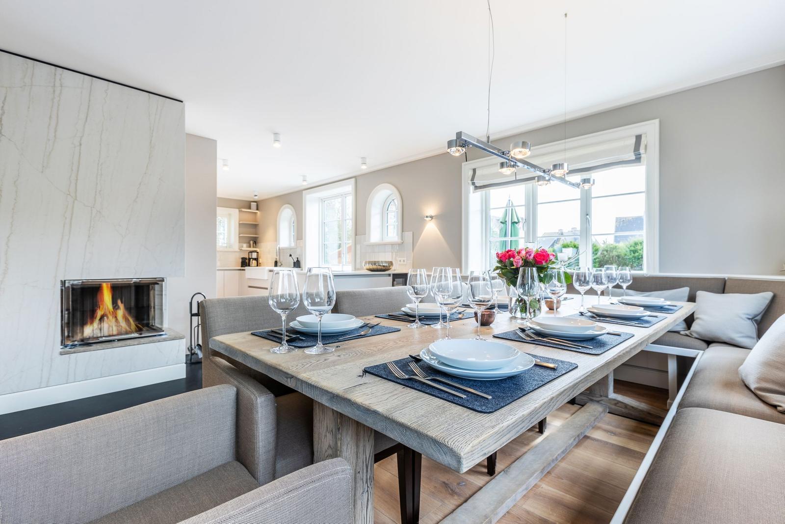 Dining area with dining table, bench, and fireplace. Windows with view outside.