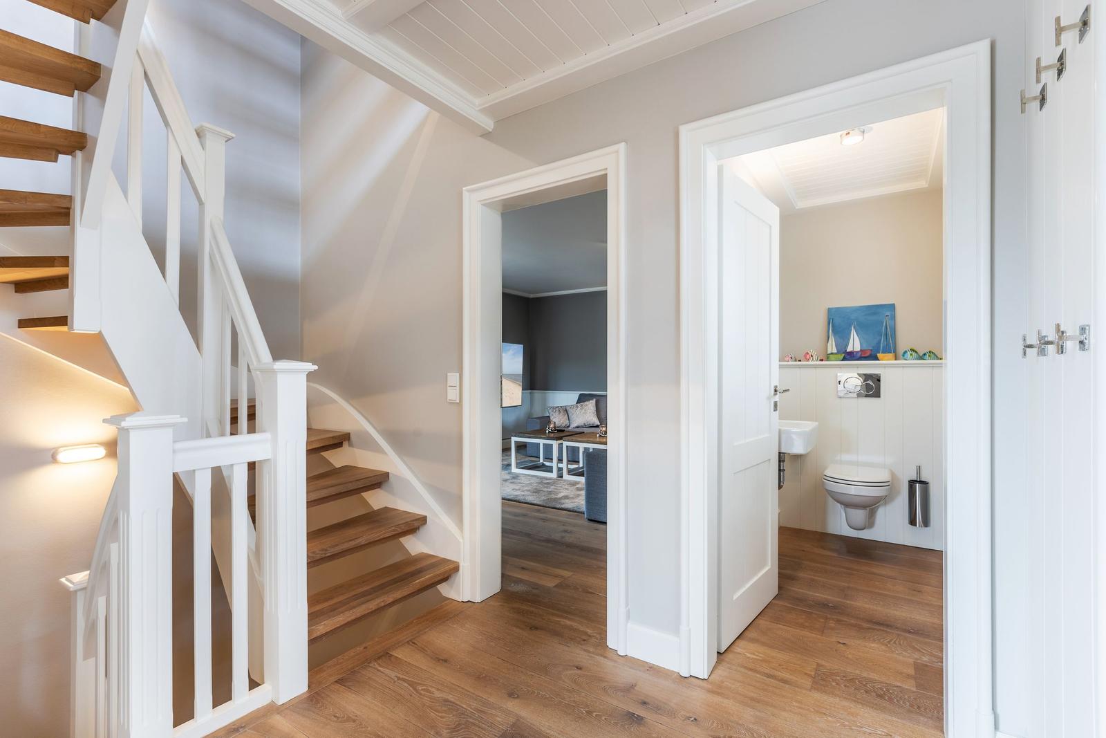 House with wooden staircase, living room, and bathroom in hallway.