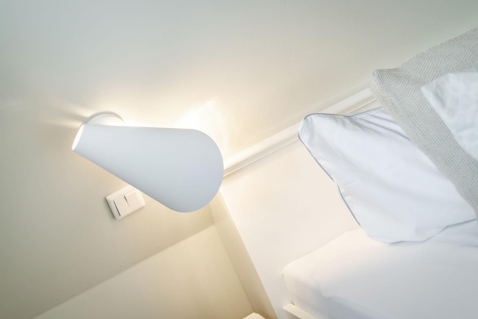 Living room with white bed and wall lamp