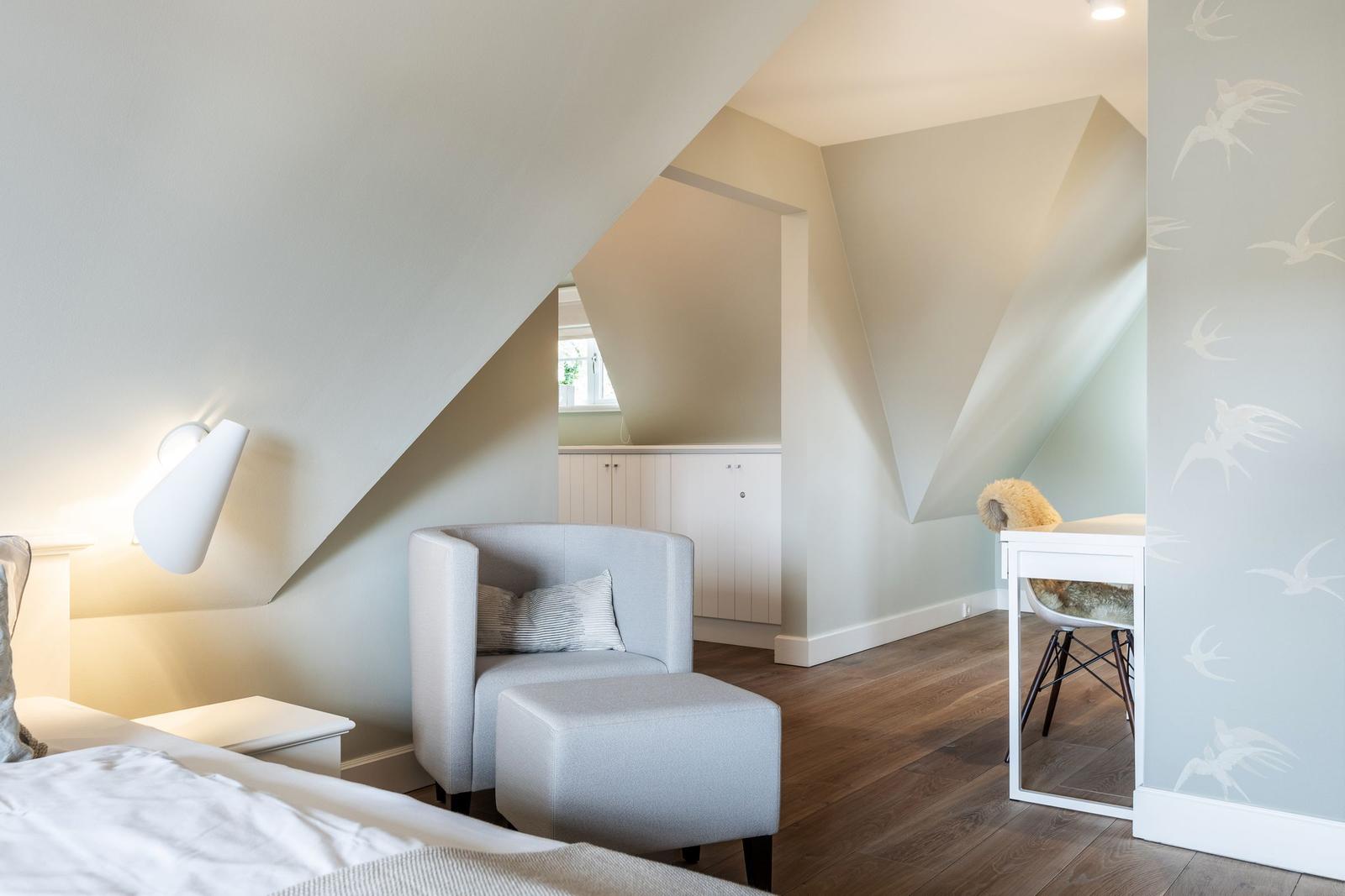Bedroom with armchair, desk, and sloped ceiling