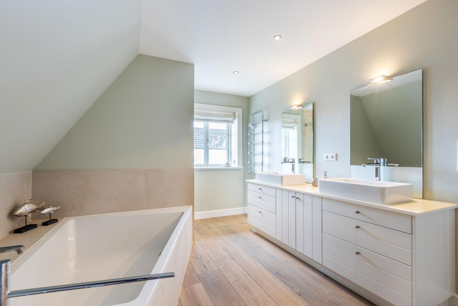 Bathroom with bathtub, sinks and wooden floor