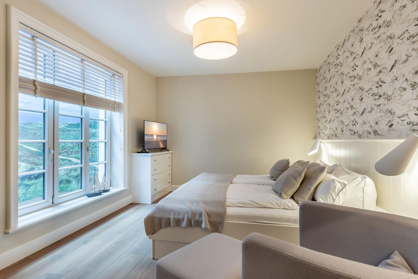 Bedroom with bed, window, and wall with bird motif