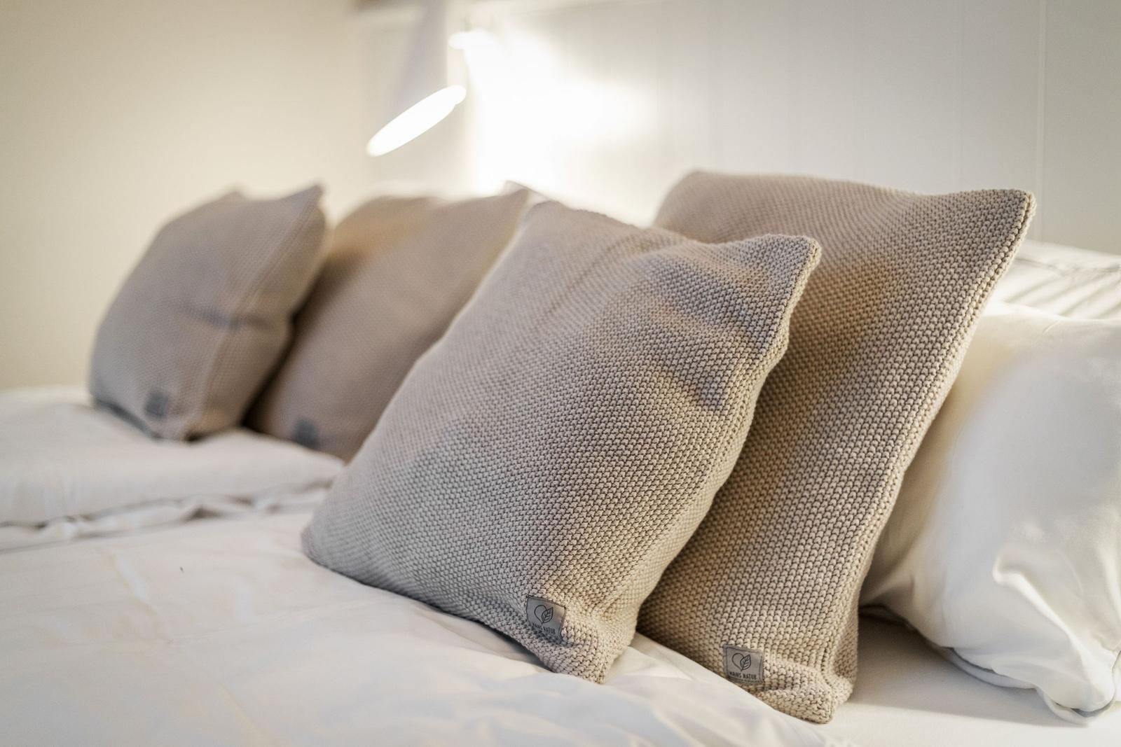 Bed head with multiple pillows and a lamp in the background.