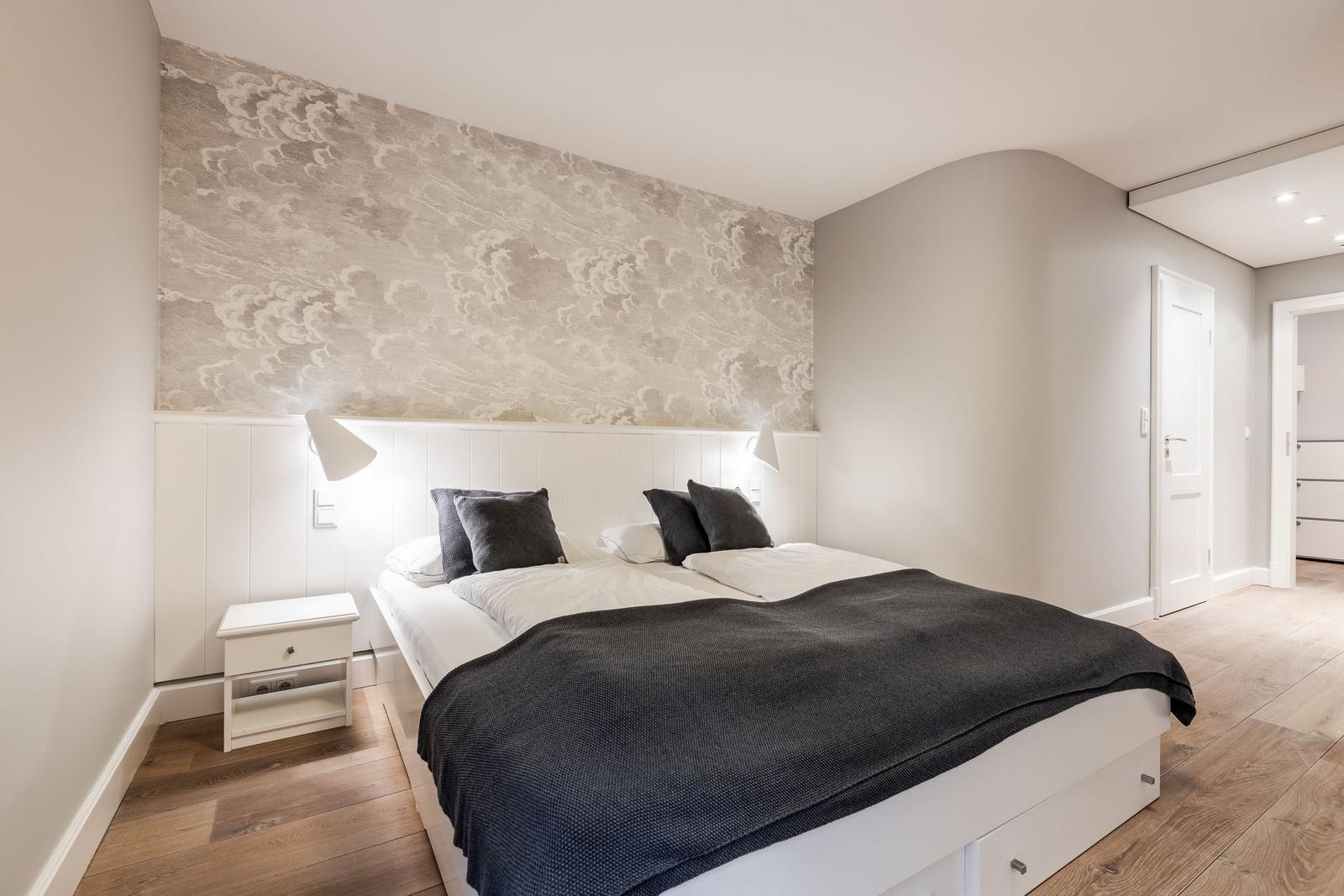 Bedroom with bed, nightstand, and patterned wall.