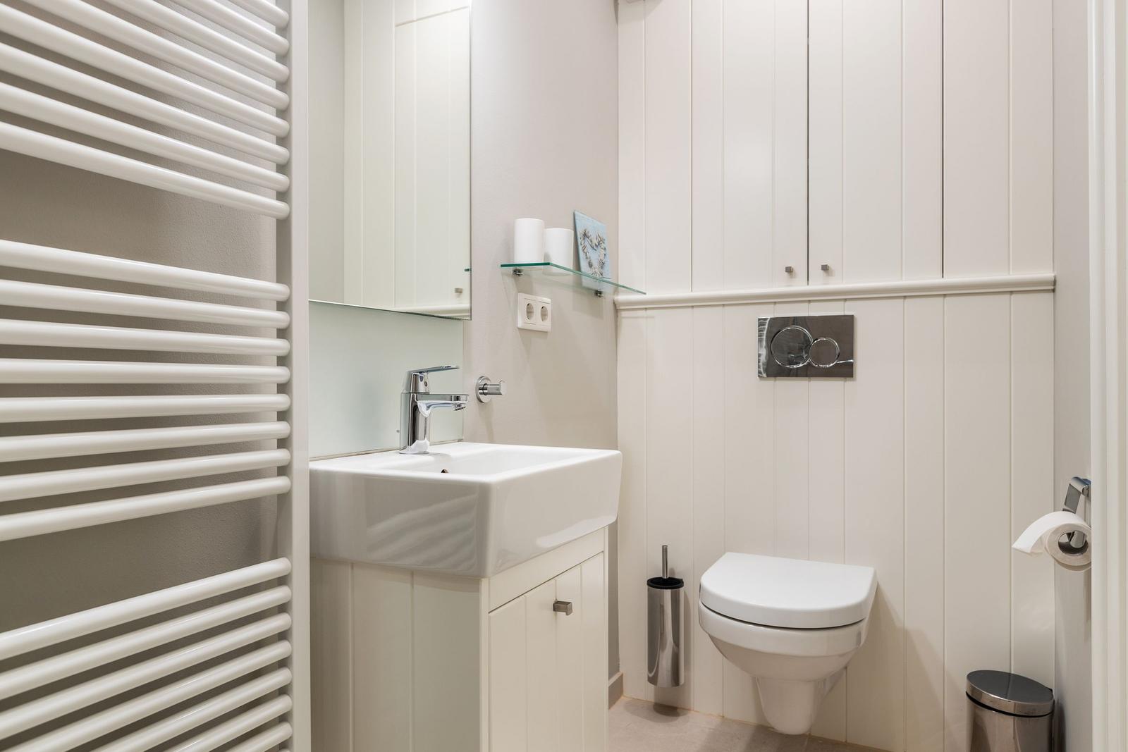 Bathroom with sink, toilet, and heater.