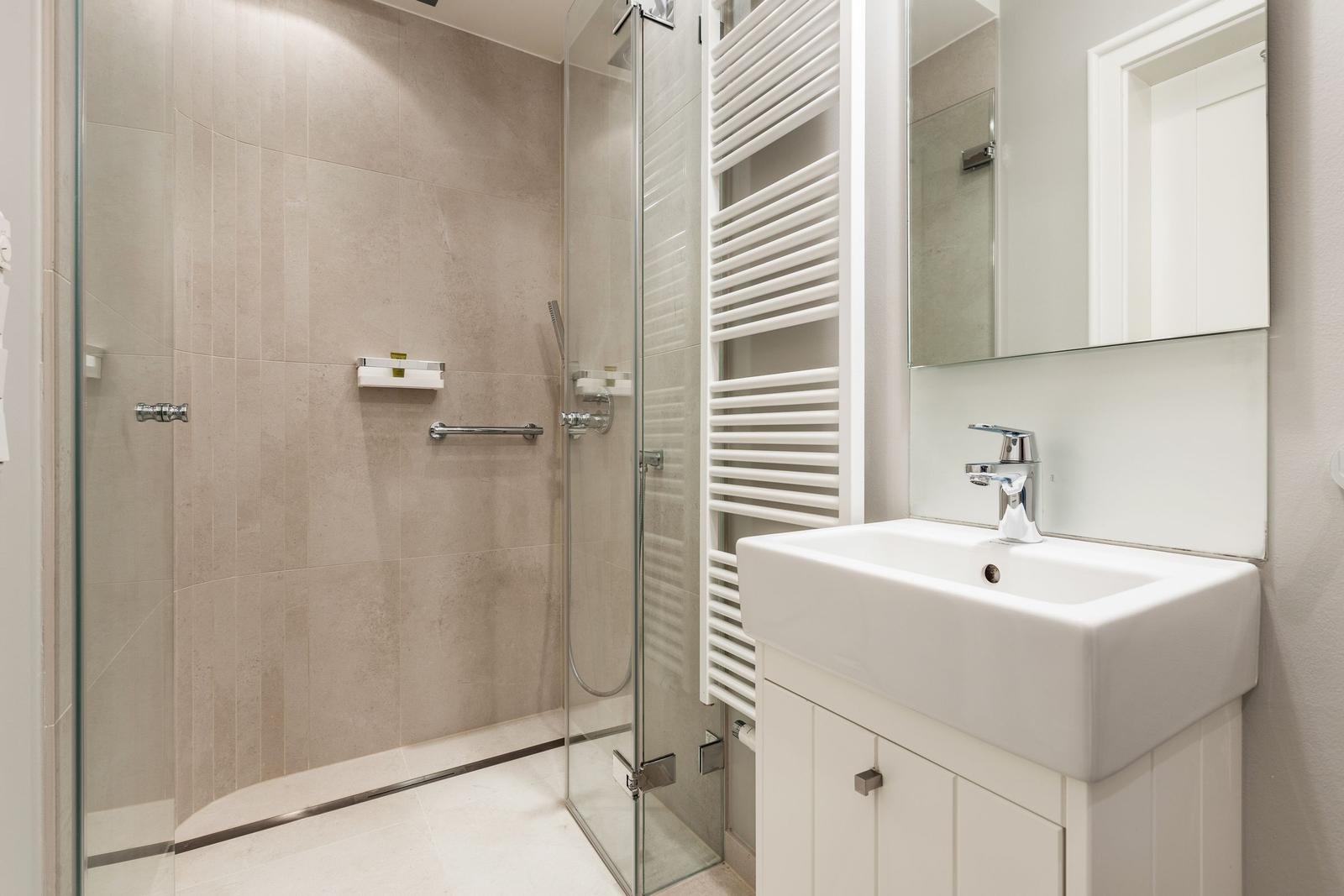 Shower cabin with glass enclosure, sink, and heater.