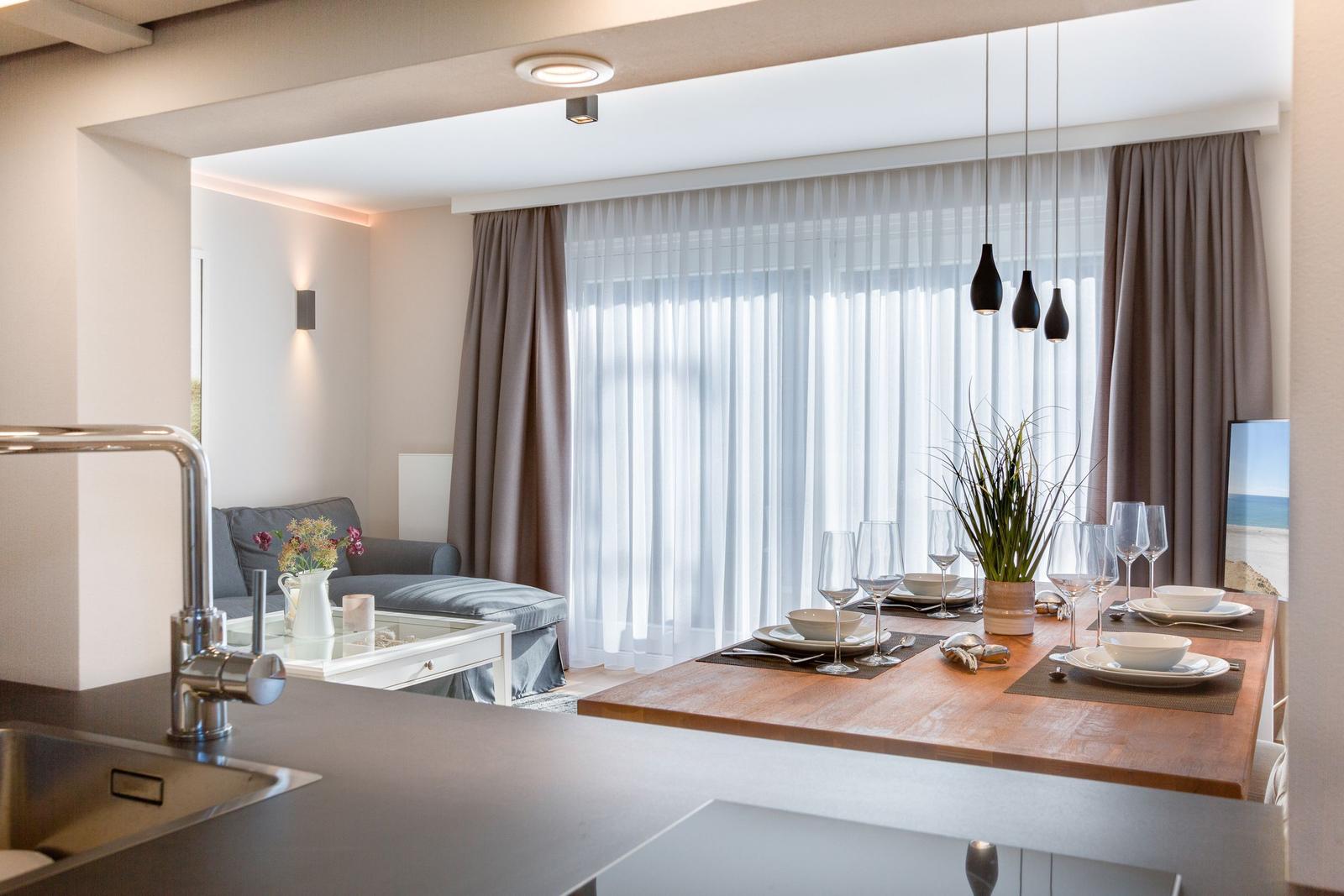 Essbereich mit Tisch, Stühlen und Fenster. Küche im Vordergrund.
