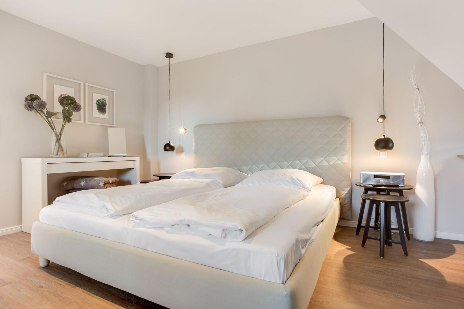 Schlafzimmer mit Bett, Nachttisch und Wandlampen.