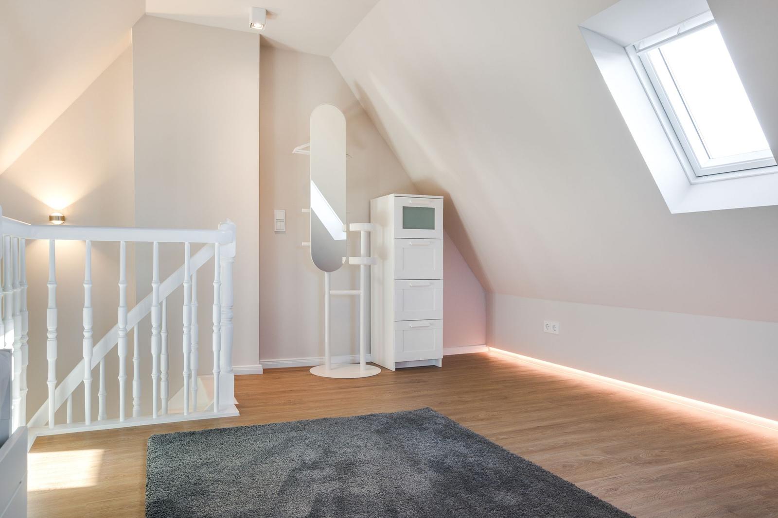 Dachgeschosszimmer mit Dachfenster, Spiegel und Schrank