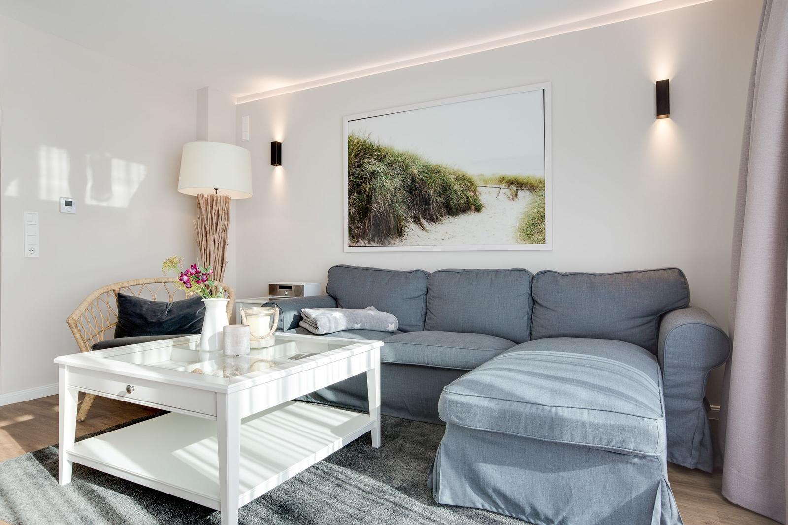 Ein Wohnzimmer mit grauem Sofa, weißem Couchtisch und Wandbild.