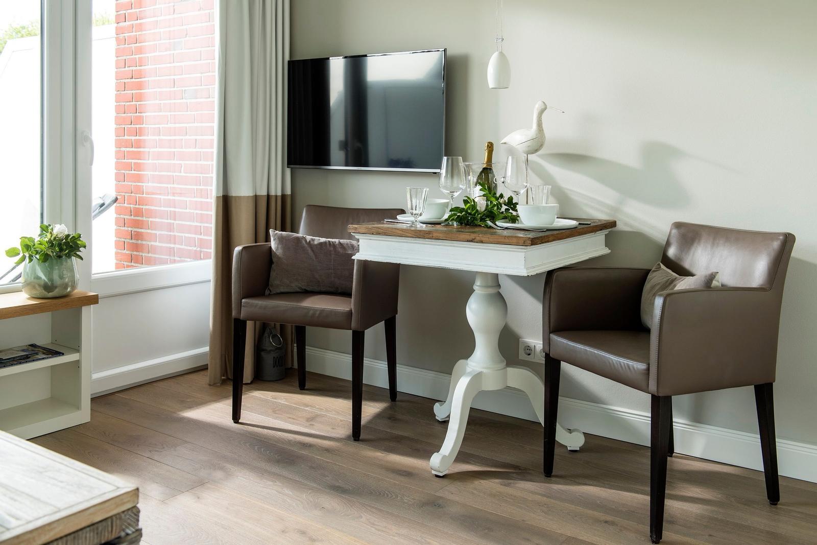 Dining area with table, two chairs, and TV mounted on the wall.