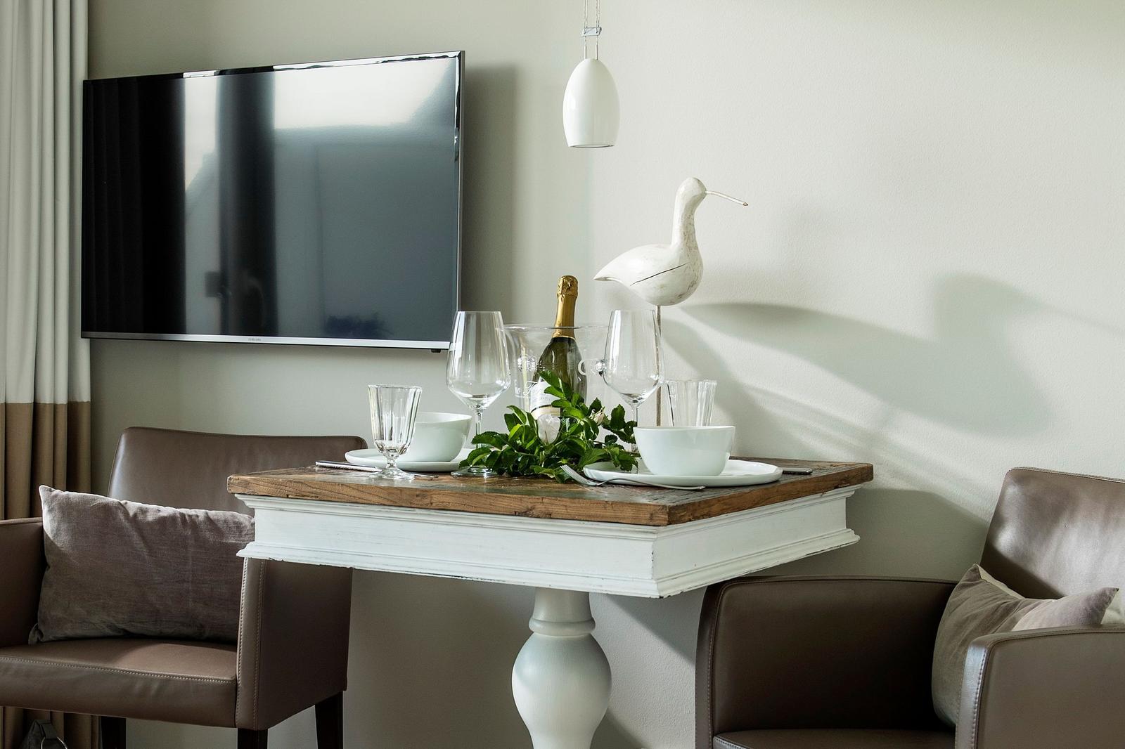 Dining table with glasses, bottle, and bird decoration in front of TV
