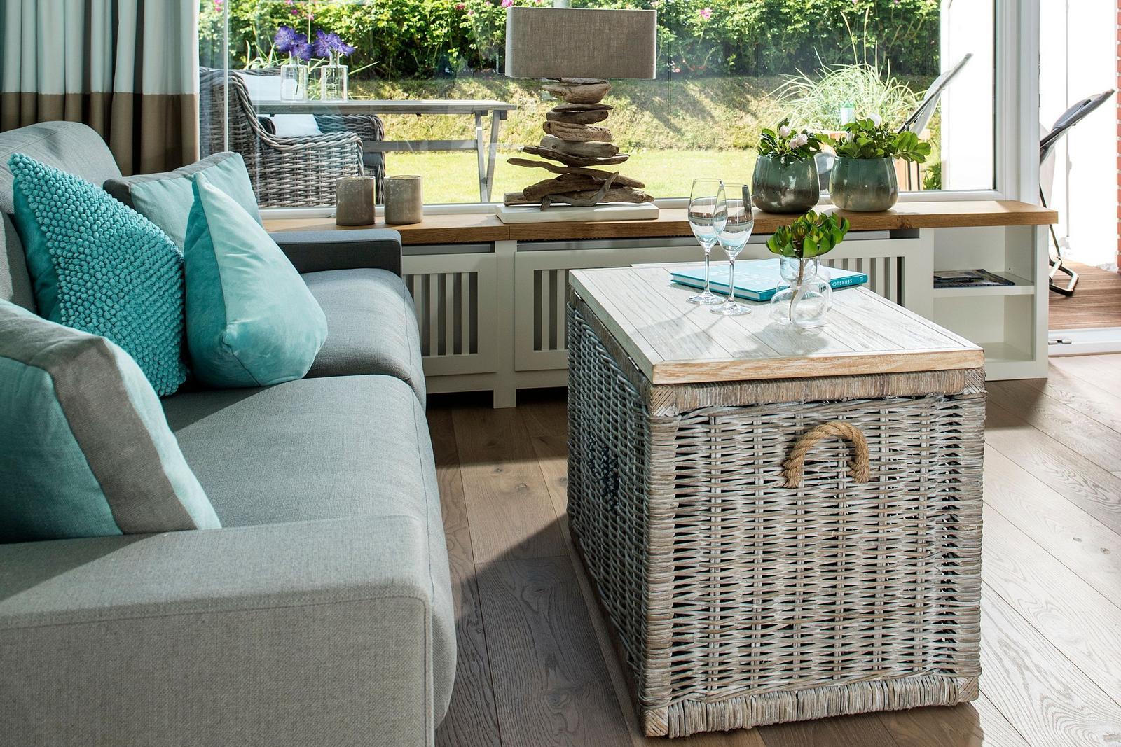 A gray sofa with turquoise cushions and a woven table.