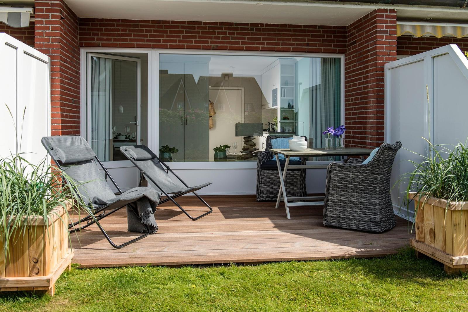Terrace with lounge chairs, table and chairs. View into the interior of the house.