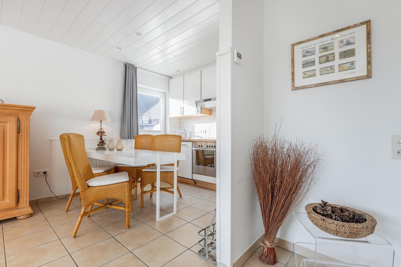 Dining area with table, chairs, and kitchen area in the background.