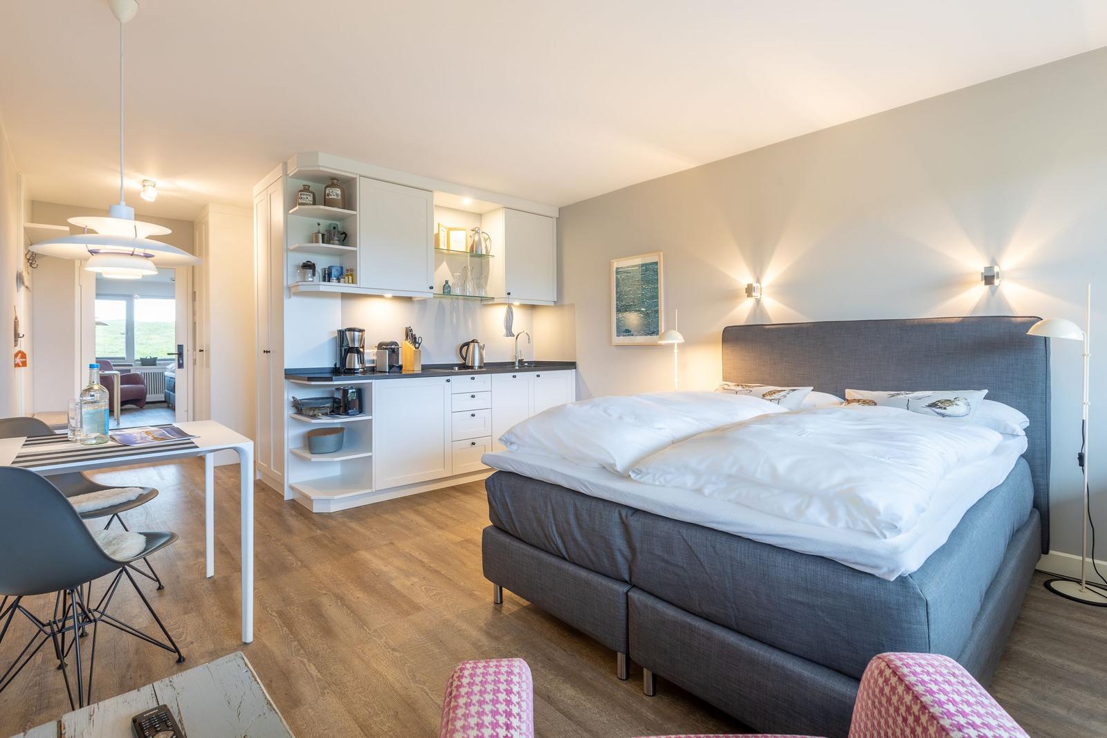 Bedroom with kitchenette and dining area. Wooden floor and modern furnishings.