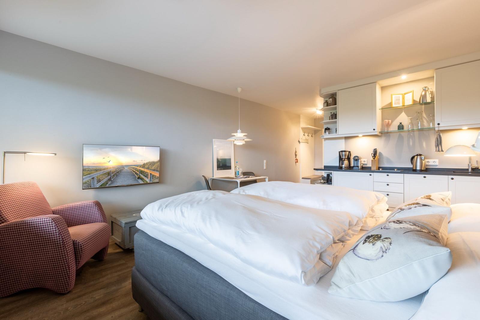 Bedroom with double bed, kitchen area, and armchair.