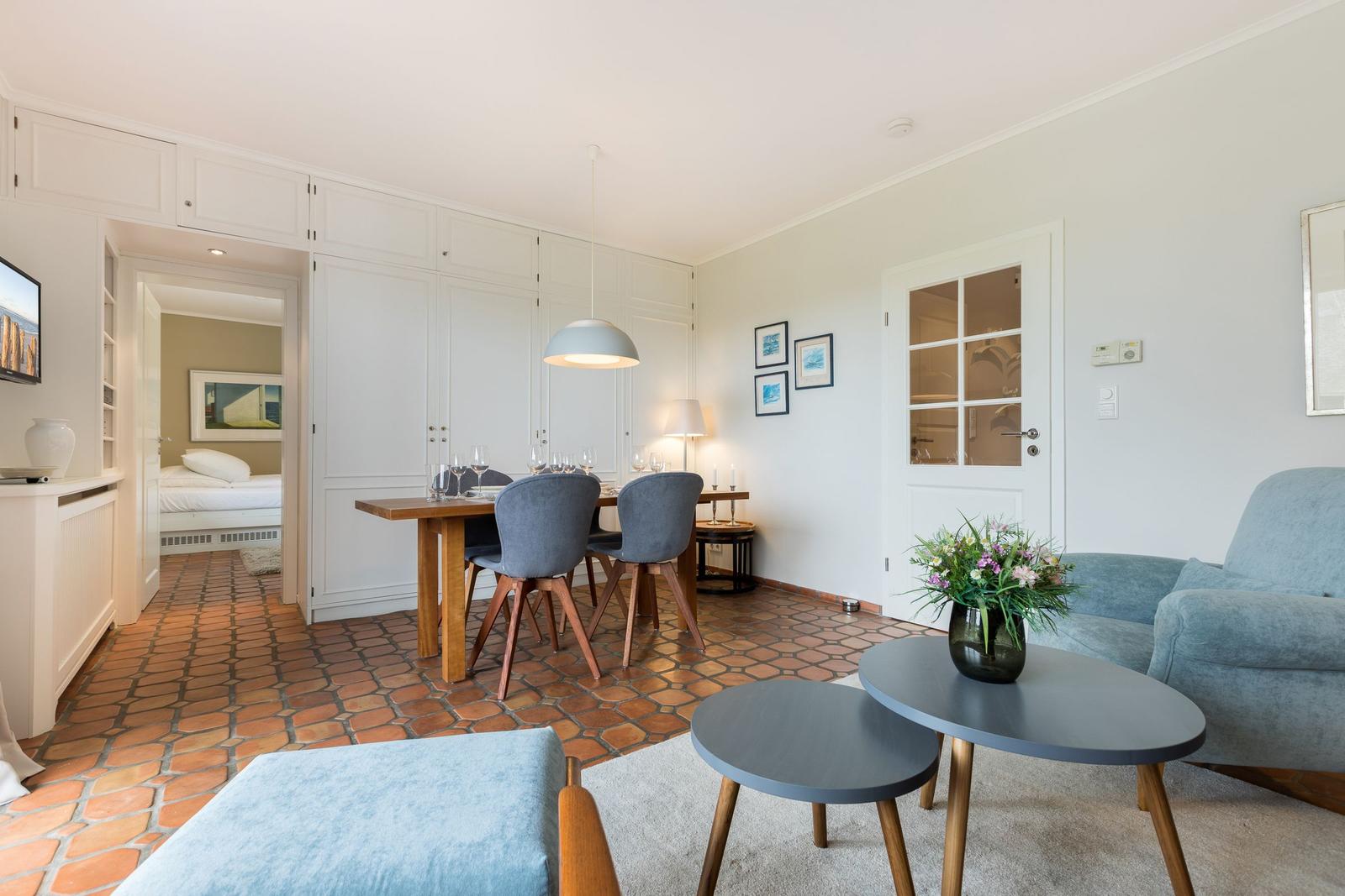 Wohn- und Essbereich mit Terrakottboden und blauem Sofa. Essbereich mit Tisch und Stühlen.