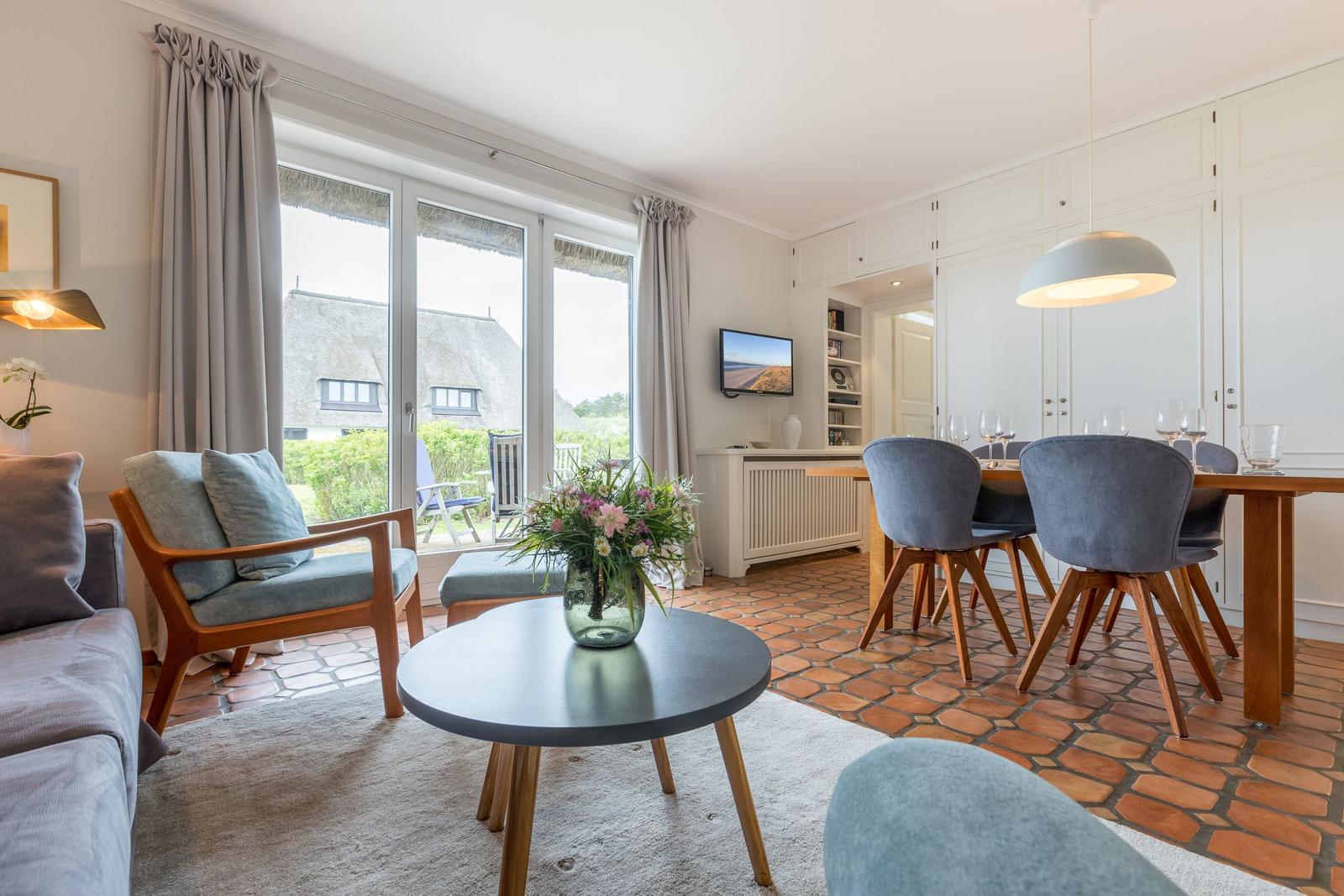 Wohn- und Essbereich mit Terrasse, Holzmöbeln und Terrakottaboden.