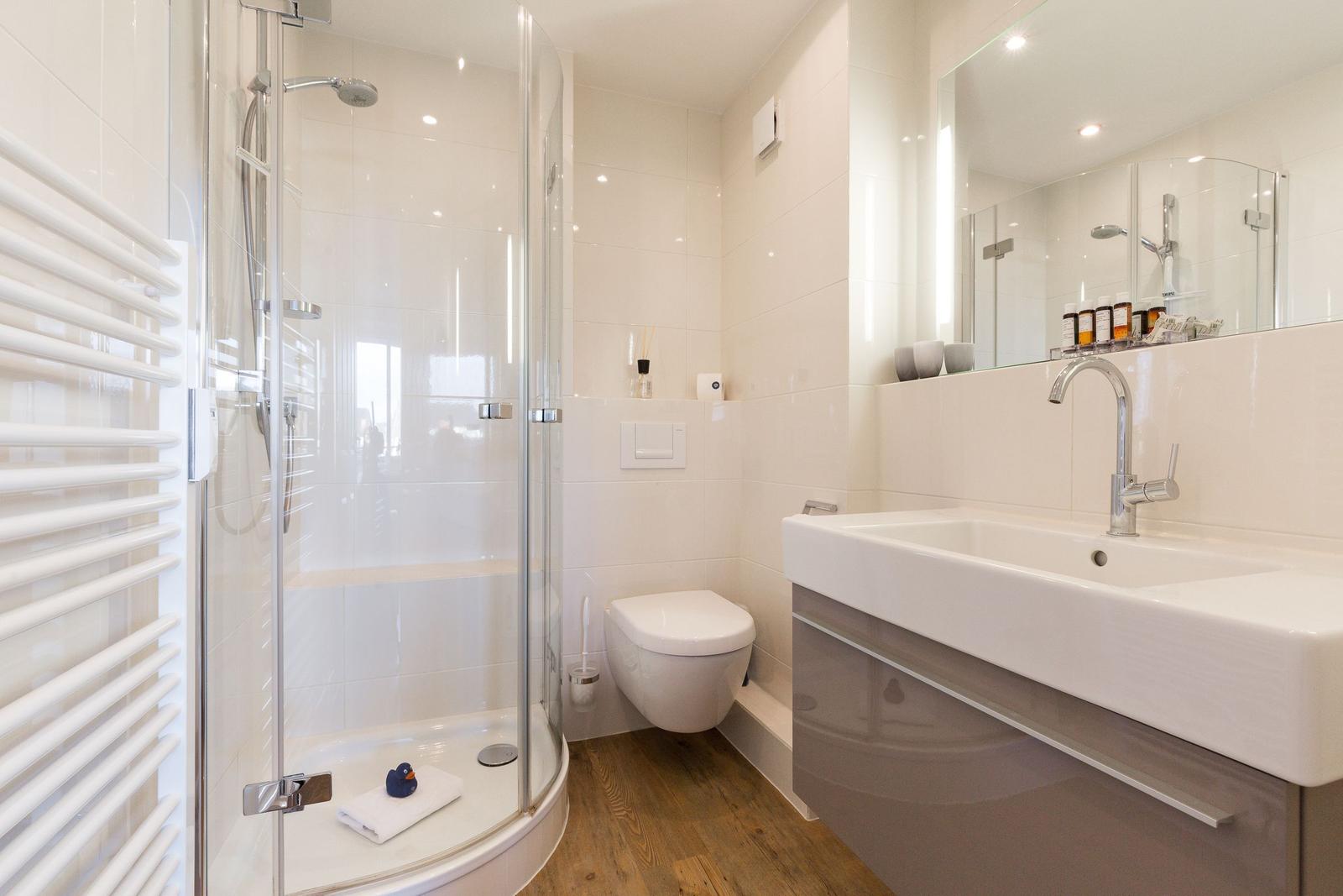 Badezimmer mit Dusche, Toilette und Waschbecken.