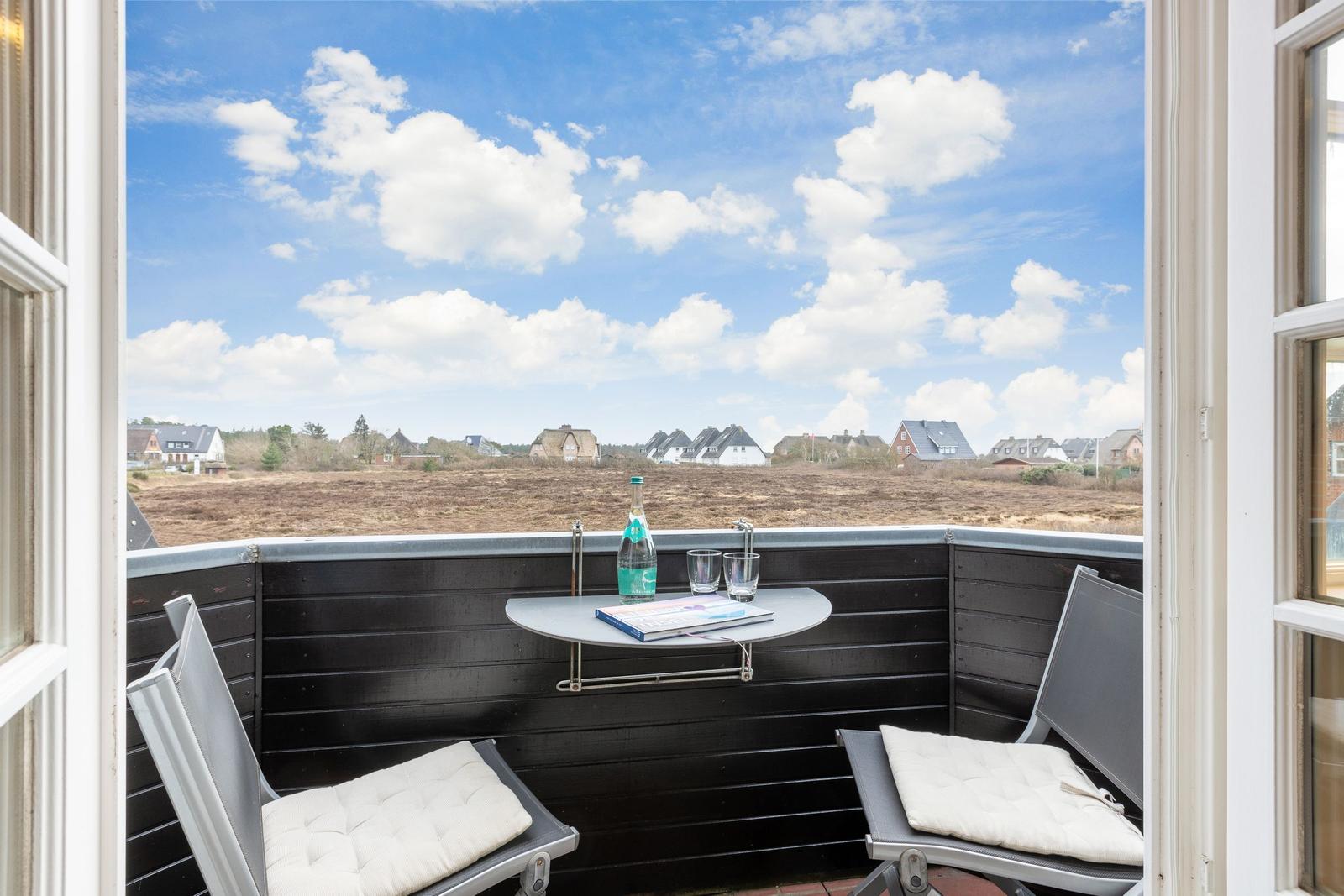 Terrasse mit Tisch und zwei Stühlen, Blick auf Feld und Häuser