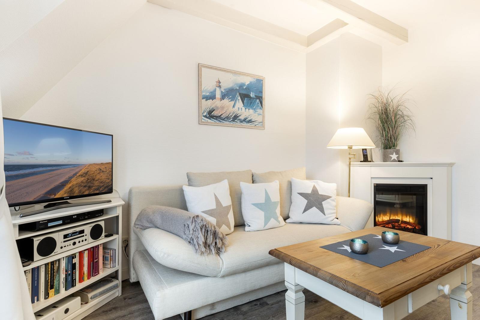 Wohnzimmer mit Sofa, Fernseher und Kaminofen.