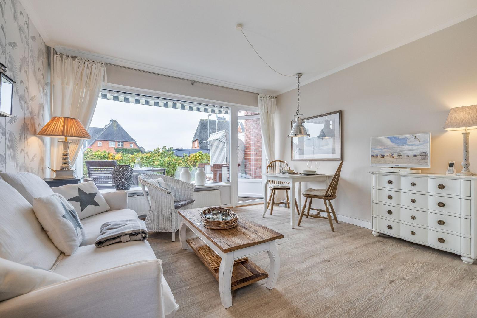 Living room with sofa, dining table, and TV cabinet. Balcony with seating area.