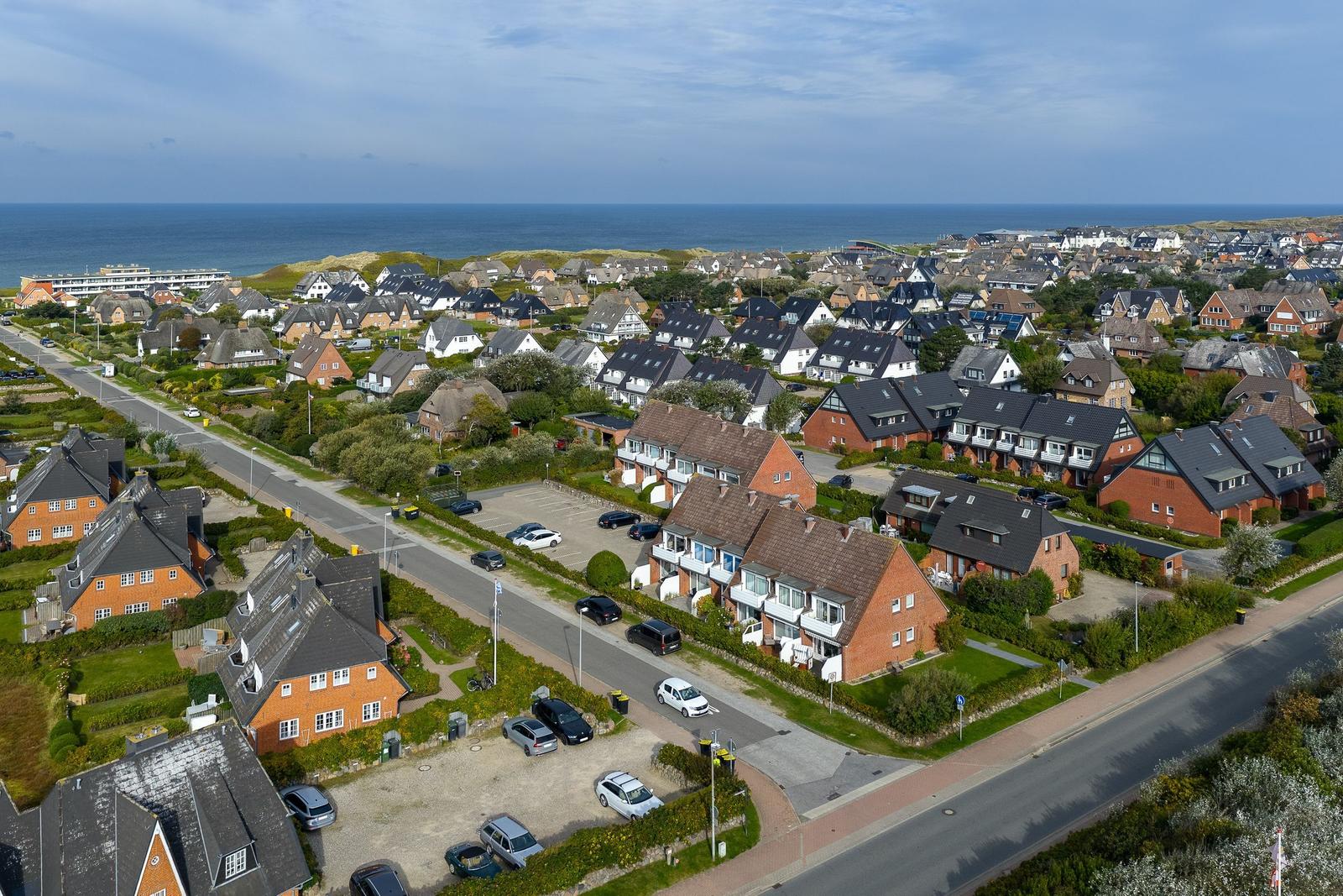 Aerial view of coastal village with houses and sea in background.