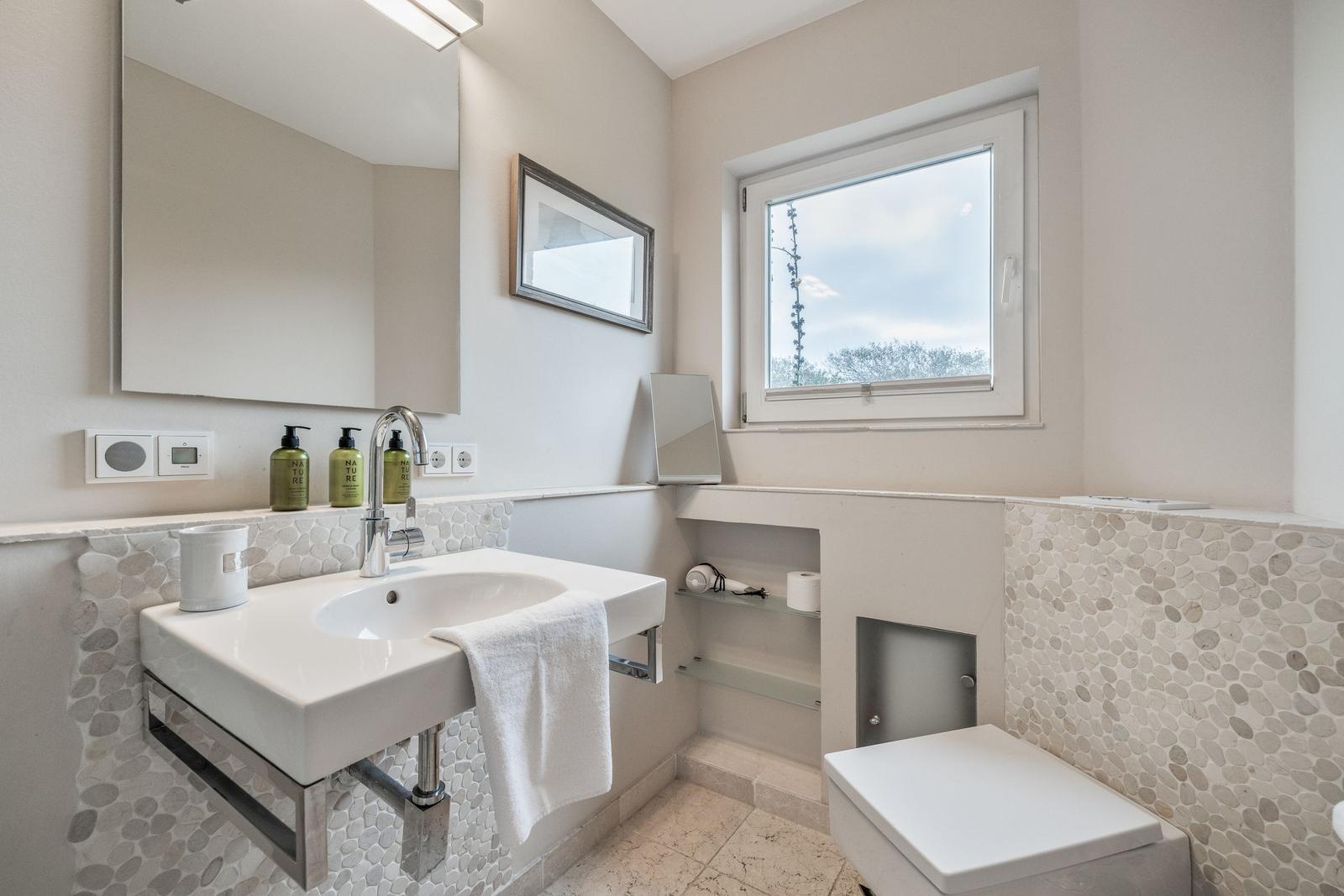 Bathroom with sink, mirror, toilet, and window