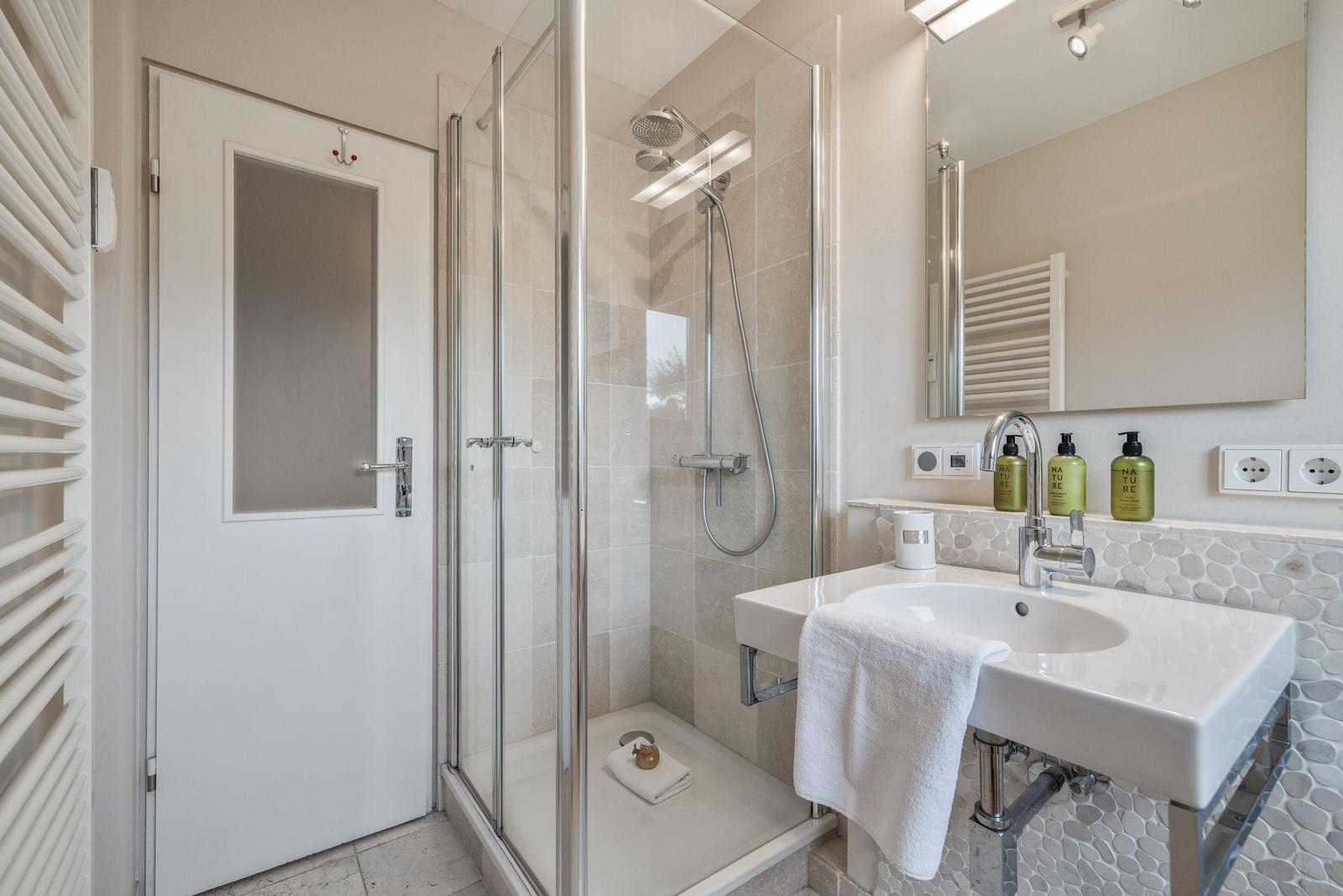 Shower area with shower cabin, sink, and mirror