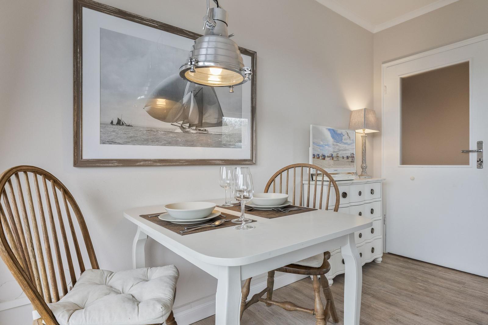 Dining room with table, chairs, and wall art of sailboats.