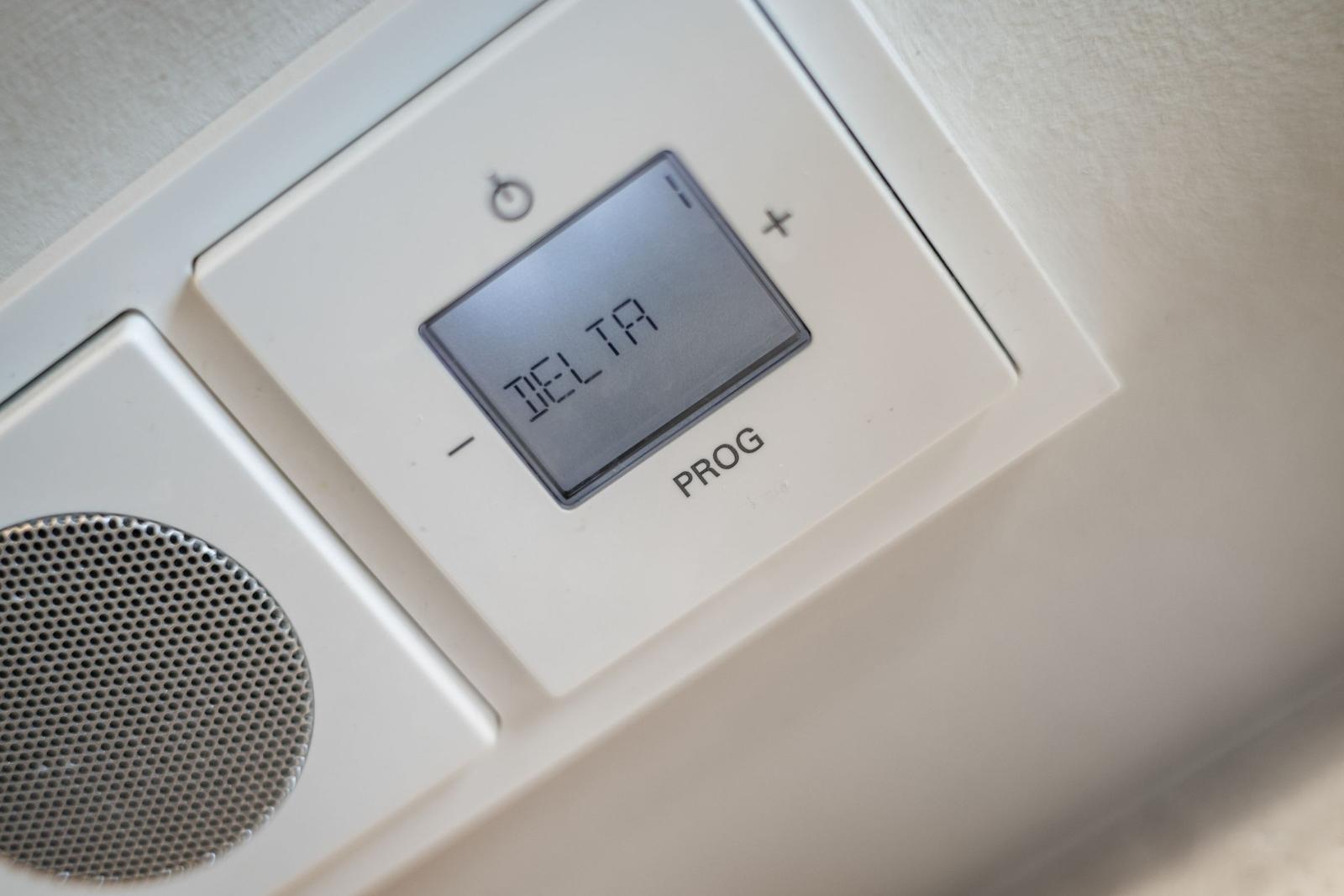 Digital thermostat with display and control buttons.
