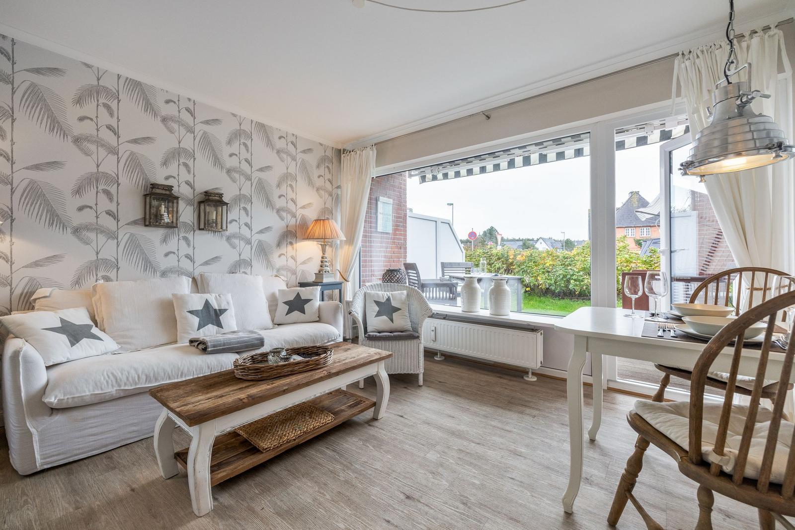 Living and dining area with sofa, table, and view of balcony.