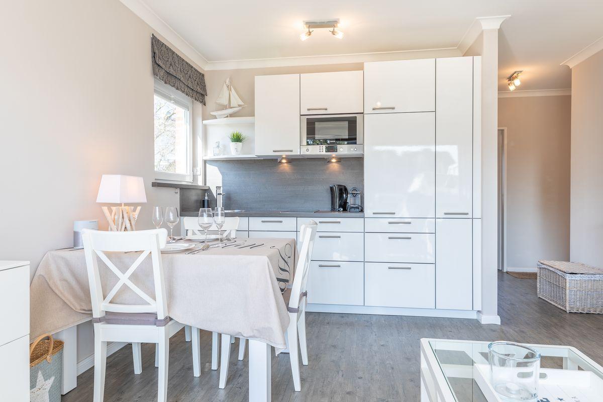Kitchen with dining area, white built-in kitchen, and table with chairs.