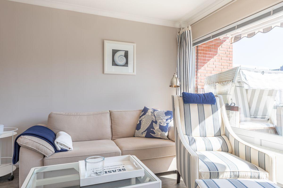 Living room with sofa, armchair, and view to balcony.