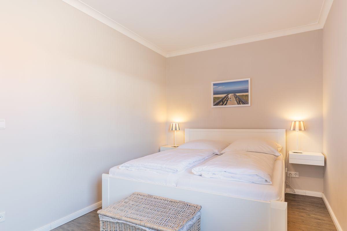 Bedroom with white bed, two nightstands, and wall picture.