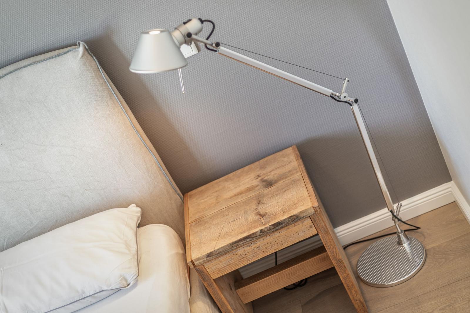 Bedroom with bed, wooden nightstand, and floor lamp.