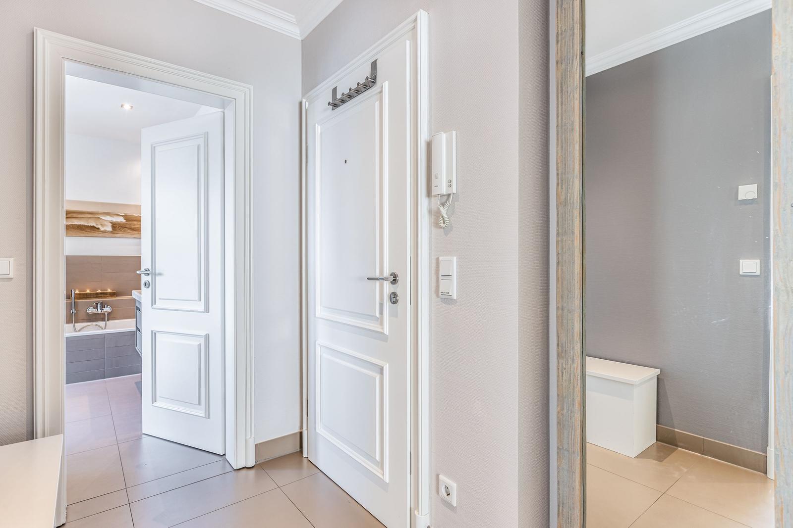 Hallway with white doors, bathroom, and another room visible.