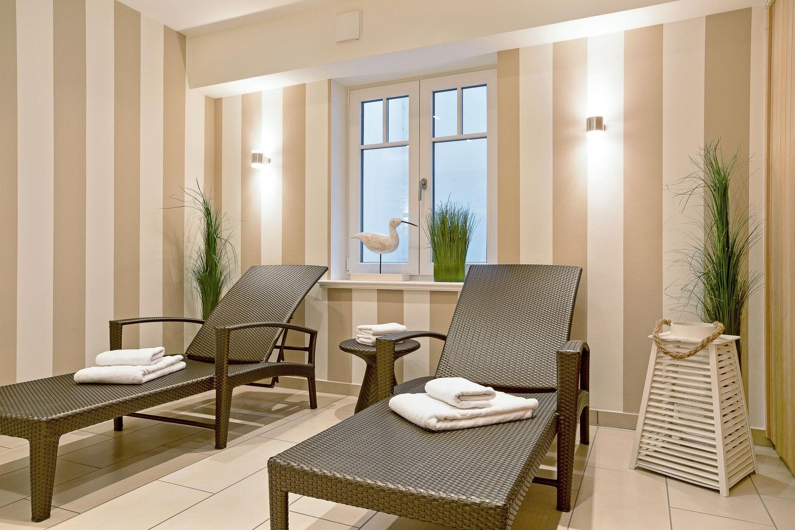 Two lounge chairs with towels near a window with striped walls and plants.