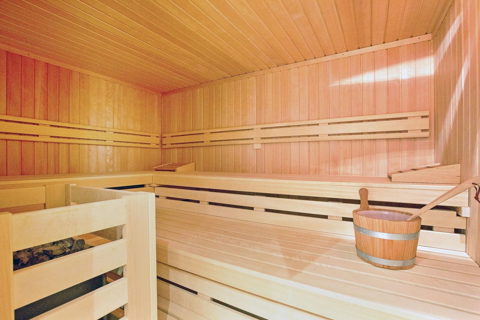 Wooden sauna with benches and bucket. Wooden walls and ceiling.