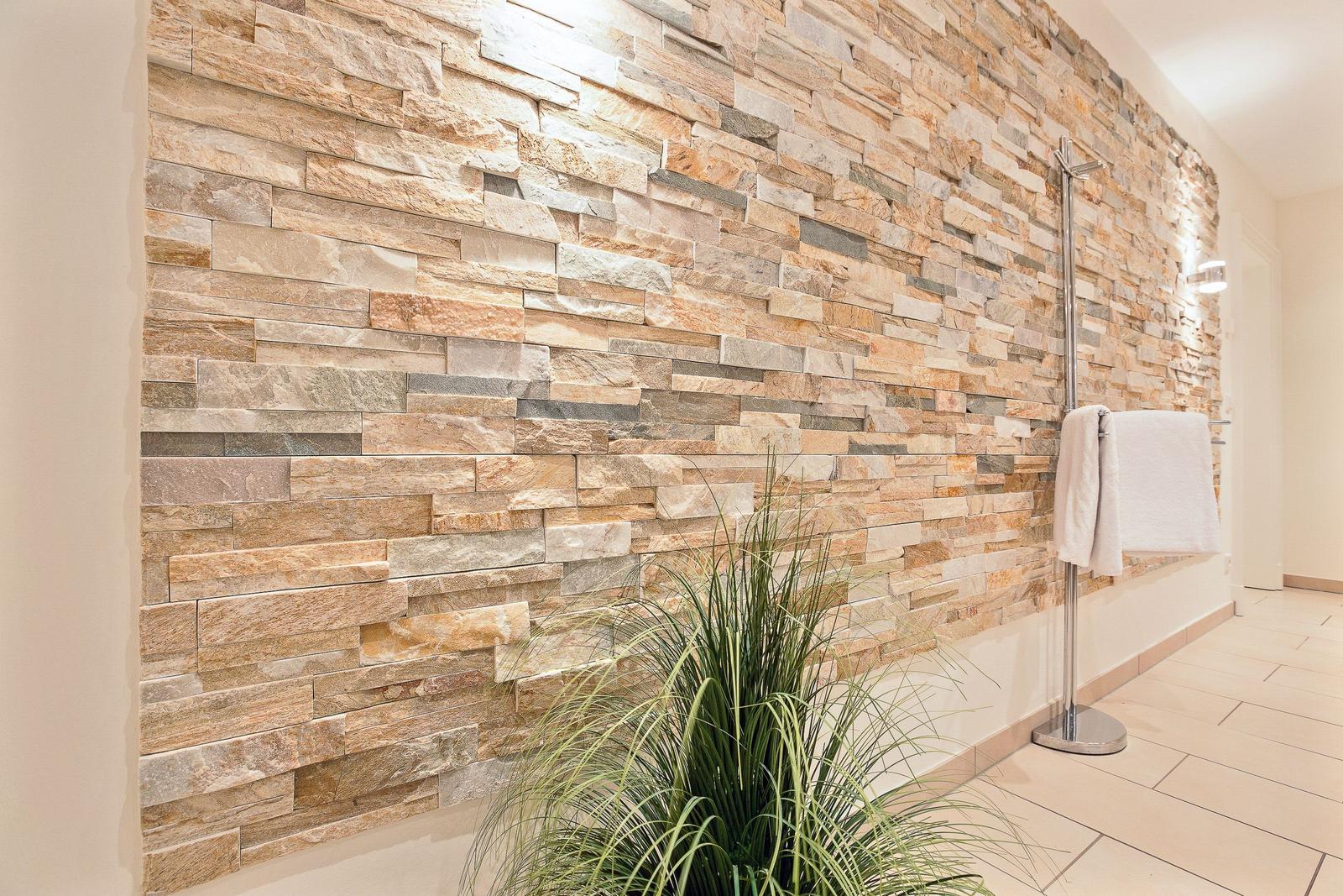 Wall with stone panels, plant, and towel rack in bathroom.