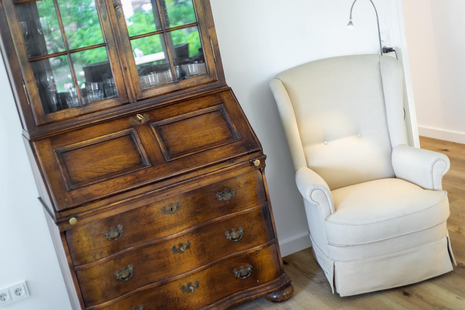 Antique cabinet and cream-colored armchair in room