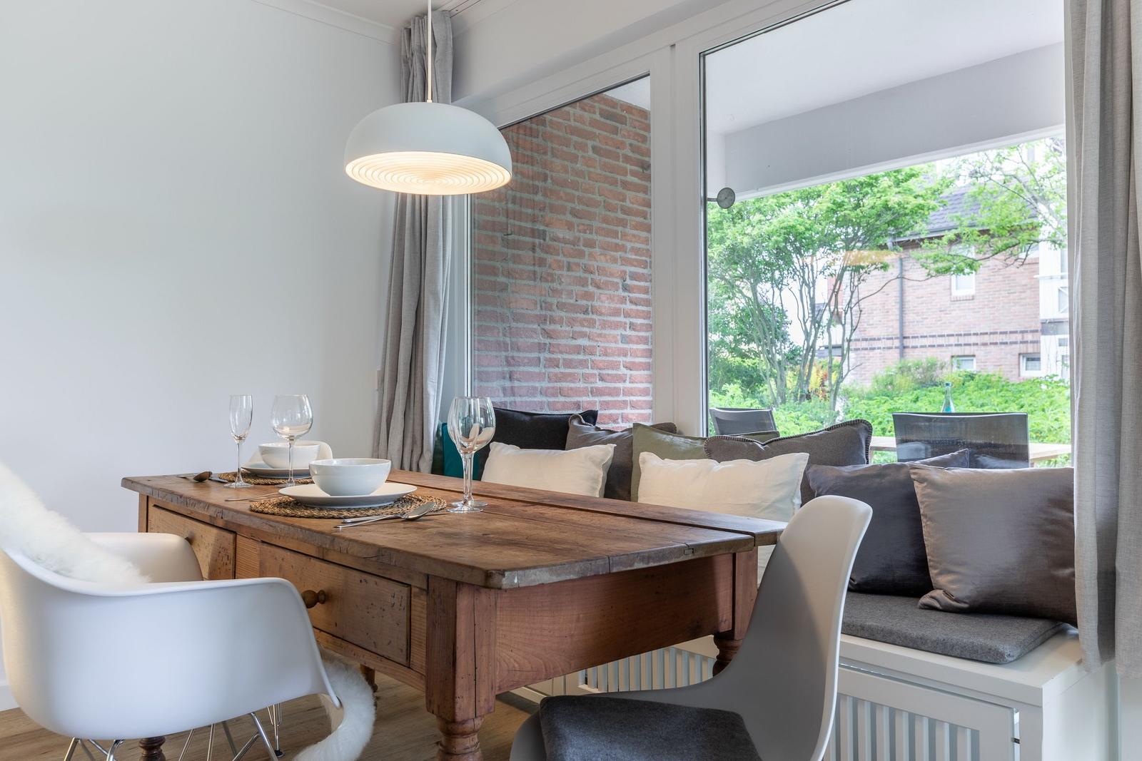 Dining room with wooden table, bench, and garden view.